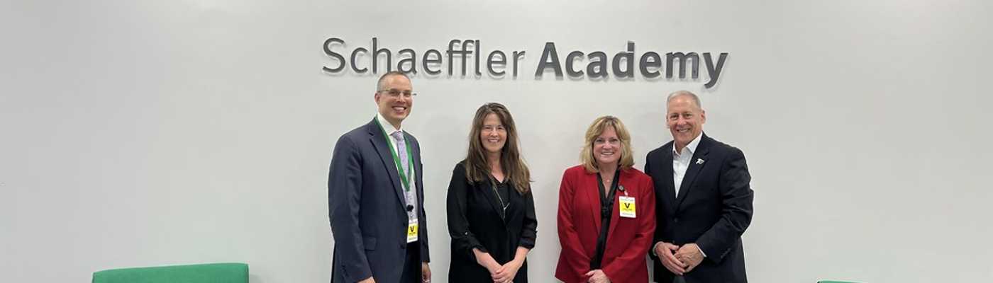 Four professionals standing together indoors beneath the Schaeffler Academy wall sign.