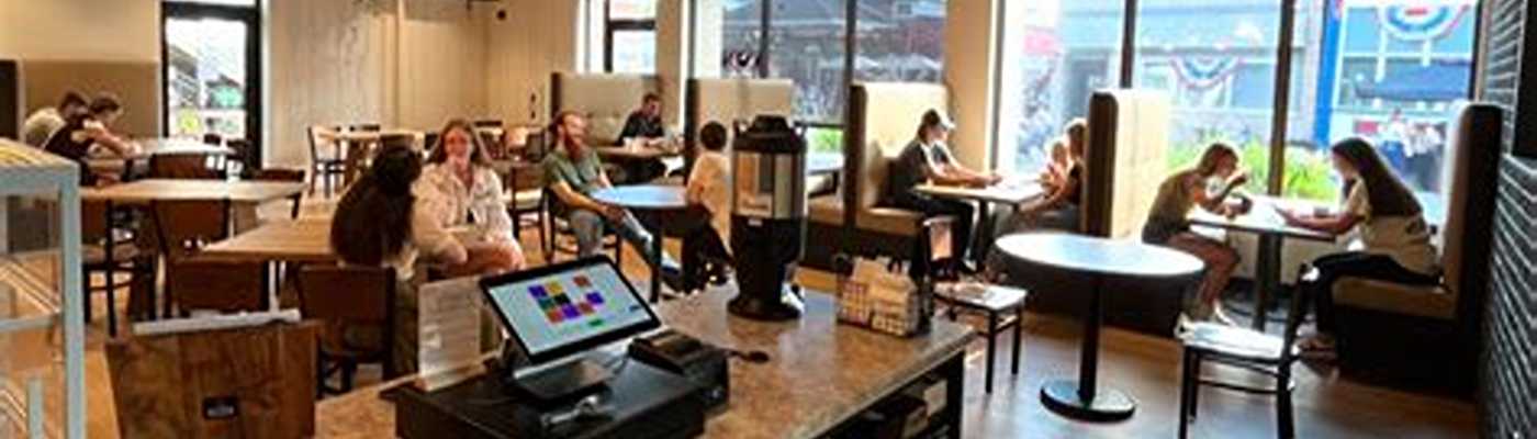 Interior view of a busy cafe with customers seated at tables and booths.