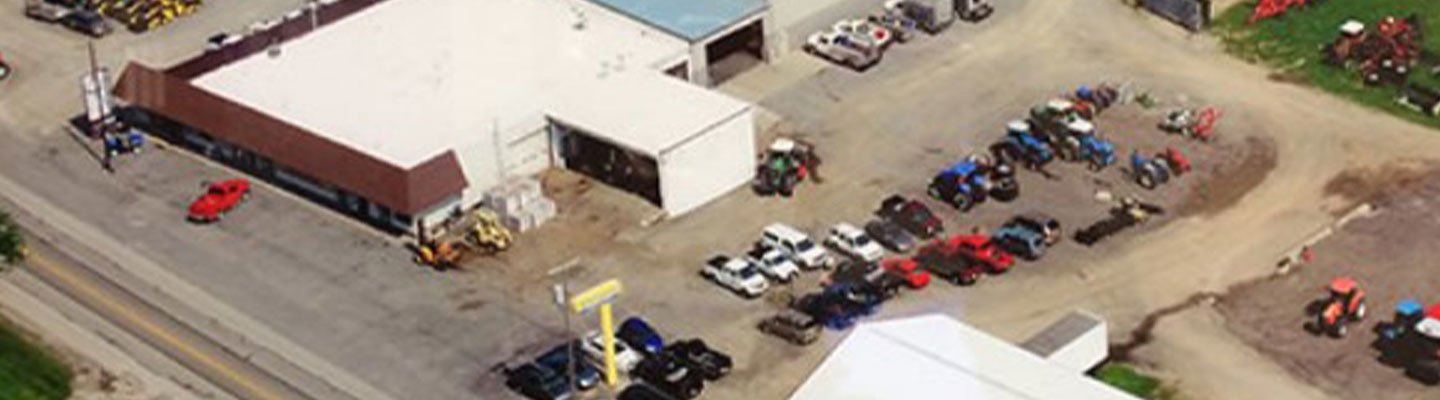 Aerial view of a commercial building and parking lot with various vehicles.