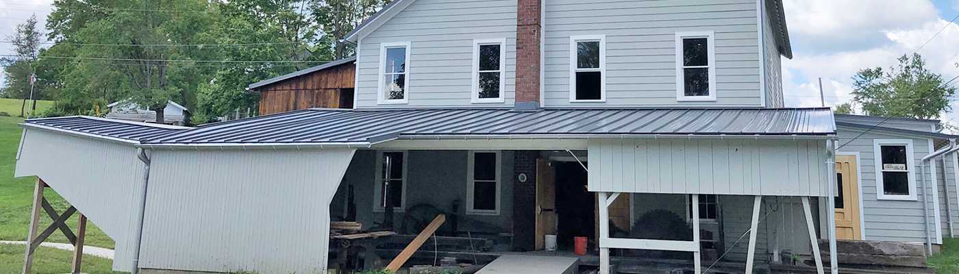 House under renovation with a metal roof porch.