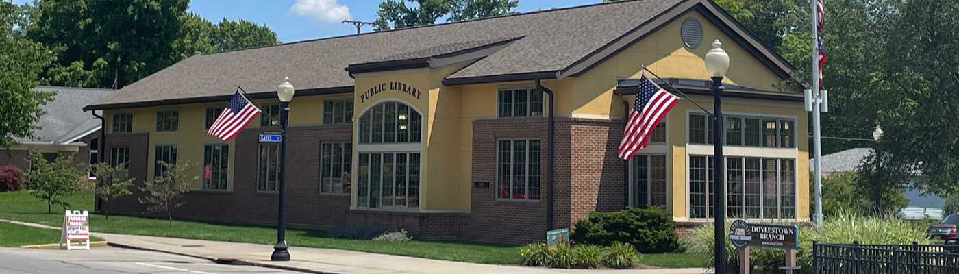 Public library building exterior decorated with American flags.