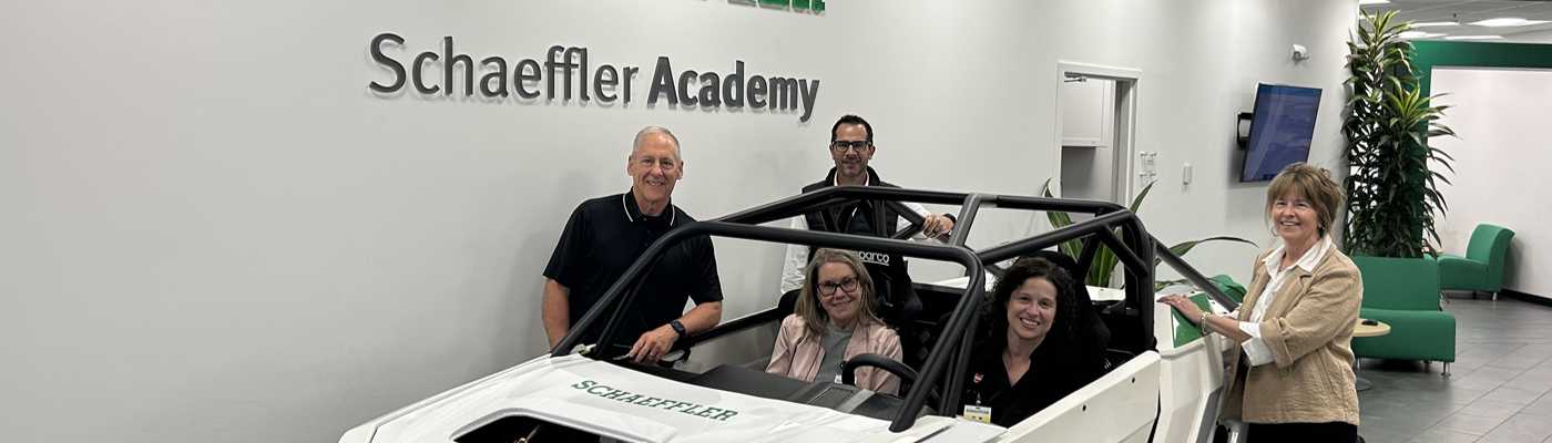 Group of people smiling together next to a custom vehicle at the Schaeffler Academy.